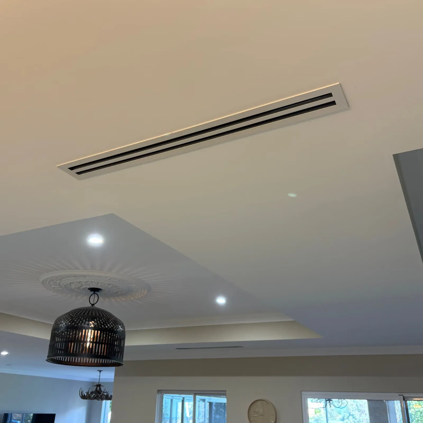 Slim linear ducted air conditioning vent in a white ceiling