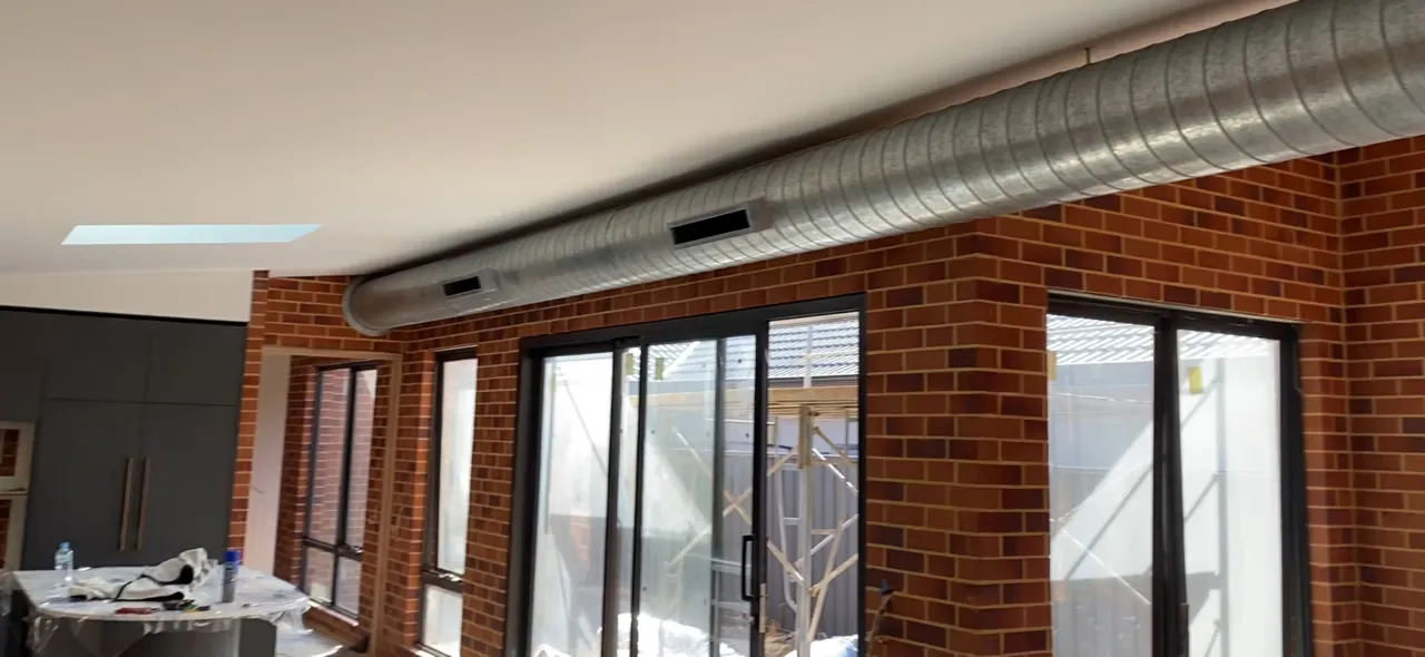 Exposed spiral ducting running along a brick wall in a renovated Melville home