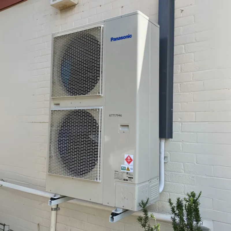 Panasonic ducted outdoor unit mounted against a white brick wall