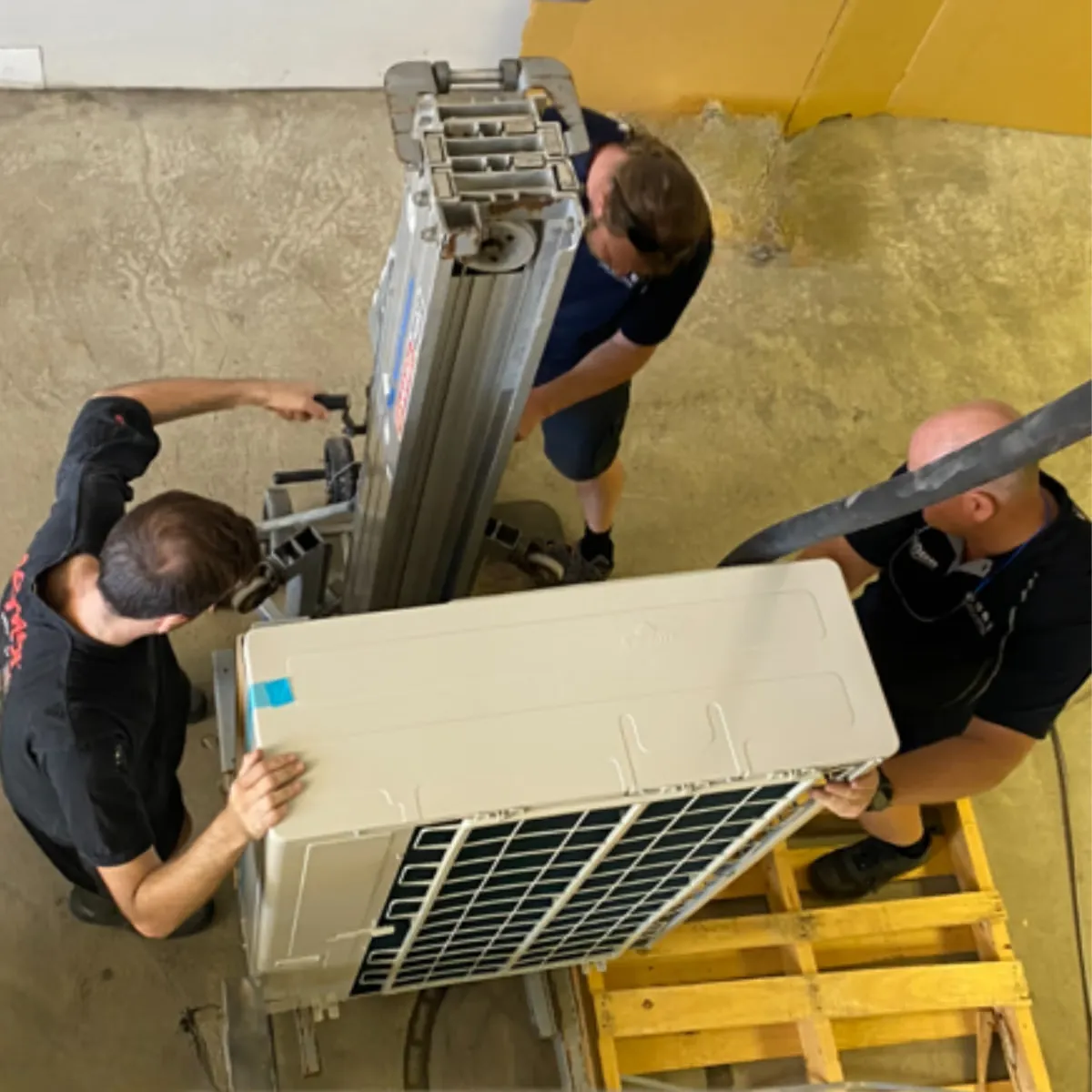 ProVent technicians lifting a ducted outdoor unit into position with a hoist